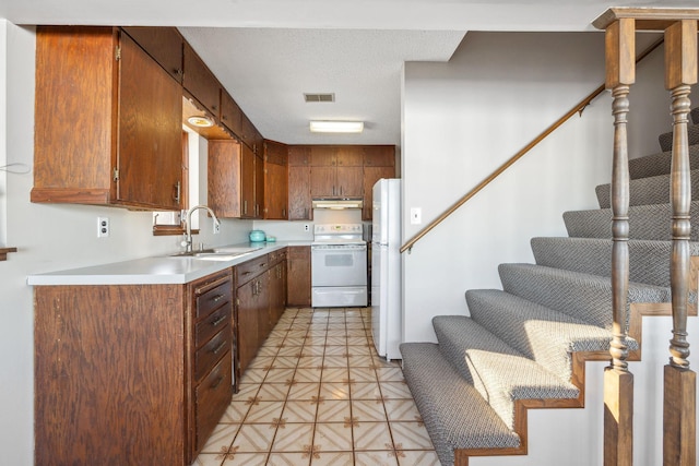 7364 Isaak Ave NW, Annandale, MN 55302 - kitchen featuring a sink, white appliances, under cabinet range hood, light countertops, and brown cabinets