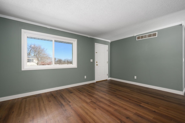 empty room featuring a textured ceiling, ornamental molding, and dark hardwood / wood-style flooring