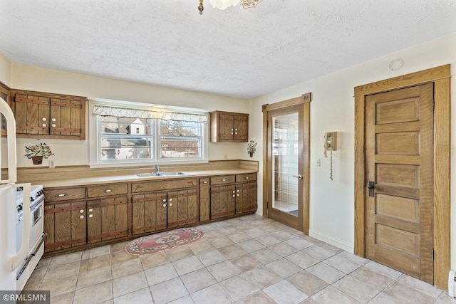 kitchen with gas range gas stove, light tile patterned floors, baseboard heating, a textured ceiling, and sink