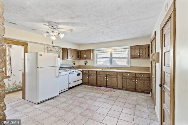 kitchen with ceiling fan, sink, white appliances, a textured ceiling, and light tile patterned floors