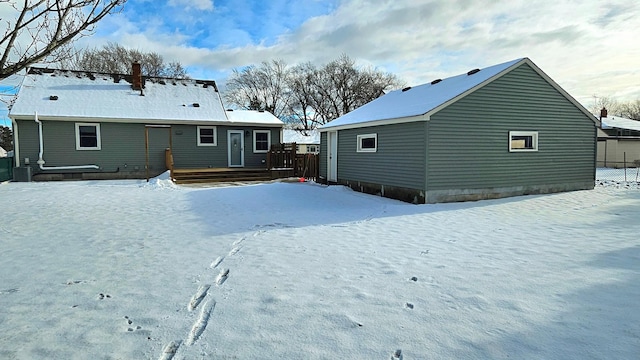 snow covered back of property with a deck