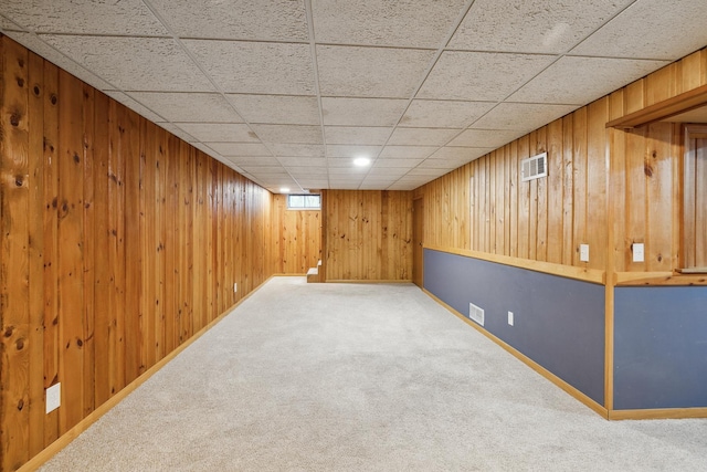 basement featuring carpet flooring and wood walls