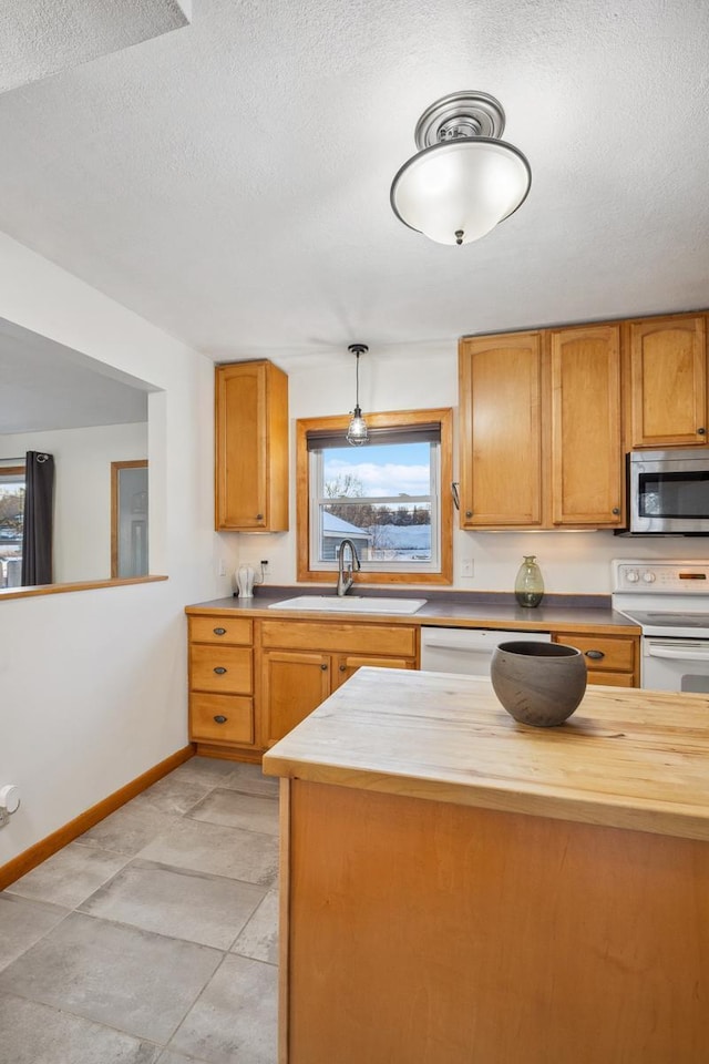 kitchen featuring sink, wooden counters, hanging light fixtures, plenty of natural light, and electric stove