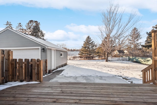 snow covered deck featuring a garage and an outbuilding