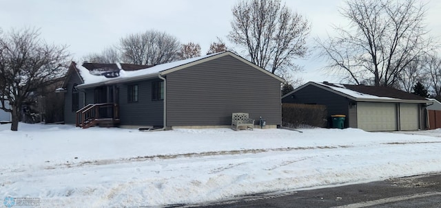 snow covered property with a garage and an outbuilding