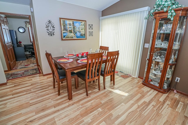 dining space featuring lofted ceiling and light hardwood / wood-style floors