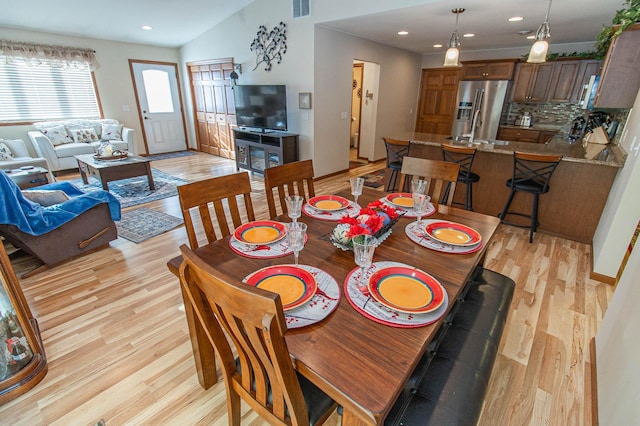 dining area with lofted ceiling and light hardwood / wood-style flooring