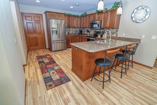 kitchen featuring kitchen peninsula, stainless steel appliances, tasteful backsplash, a breakfast bar, and sink