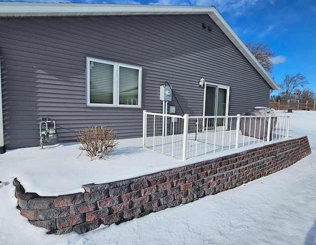 snow covered rear of property with a deck