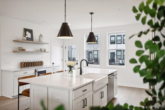 kitchen featuring white cabinetry, stainless steel dishwasher, sink, and a center island with sink