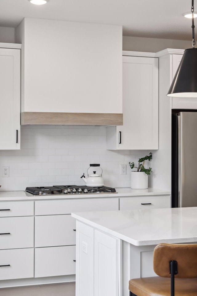 kitchen featuring stainless steel appliances, decorative backsplash, and white cabinets