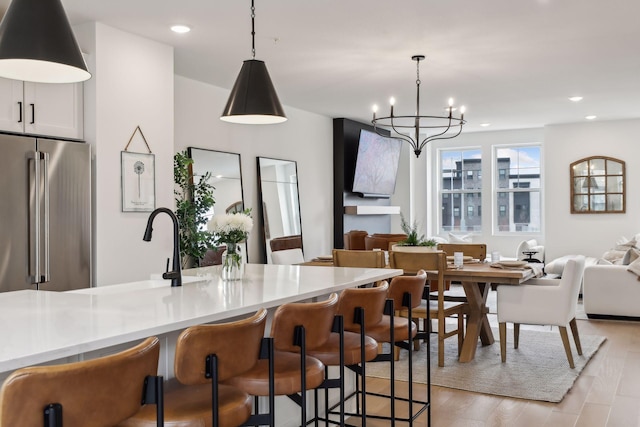 kitchen with high end fridge, hanging light fixtures, an inviting chandelier, and light wood-type flooring