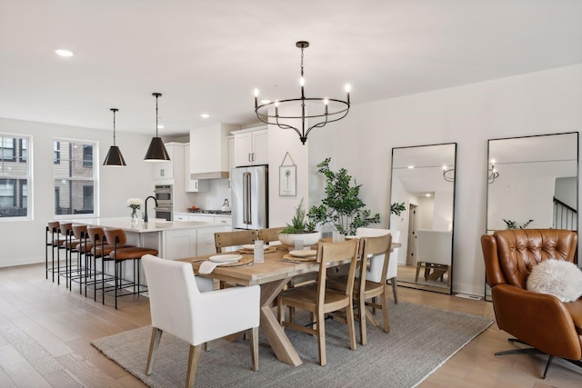 dining space with light hardwood / wood-style floors and a notable chandelier