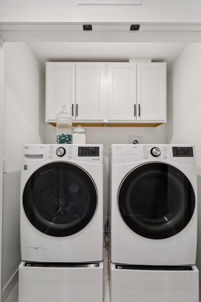 laundry room featuring washer and dryer and cabinets