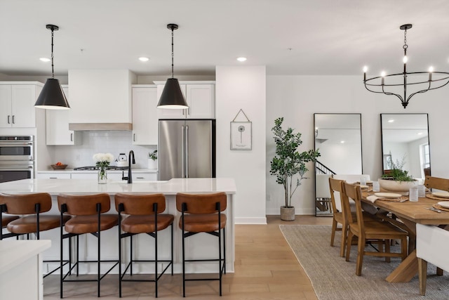 kitchen featuring light countertops, appliances with stainless steel finishes, premium range hood, and a kitchen bar