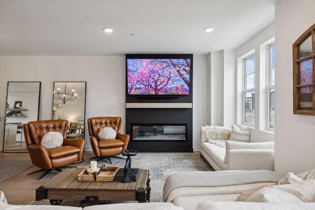 living area with a glass covered fireplace, recessed lighting, and a notable chandelier