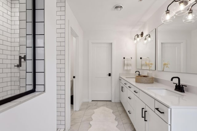 bathroom with double vanity, marble finish floor, and a sink