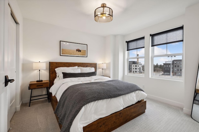 bedroom featuring light carpet, baseboards, and a closet
