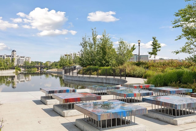 view of property's community with outdoor dining space, a patio area, and a water view