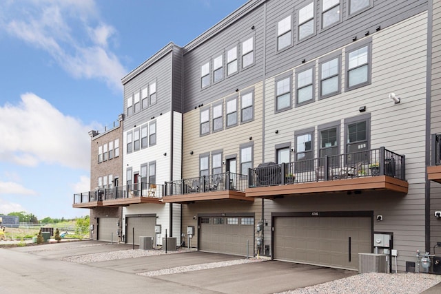 view of building exterior with an attached garage, driveway, and central AC unit