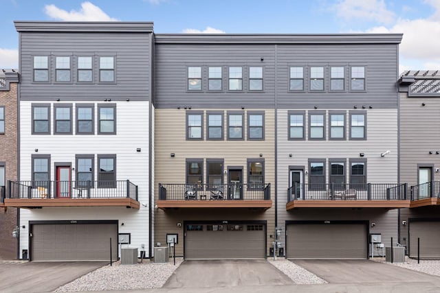 rear view of property with a garage, driveway, and central AC