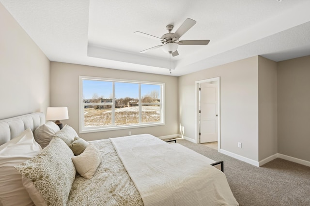 bedroom featuring ceiling fan, light colored carpet, and a tray ceiling