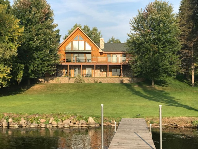 back of house with a water view and a lawn