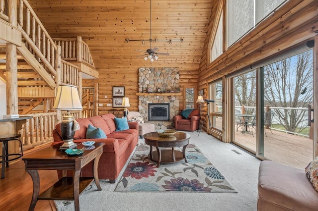 carpeted living room with ceiling fan, a fireplace, rustic walls, high vaulted ceiling, and wooden ceiling