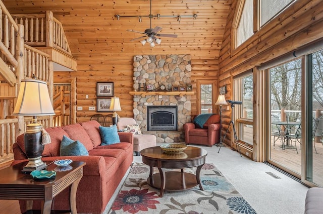 carpeted living room featuring wood ceiling, ceiling fan, a fireplace, high vaulted ceiling, and rustic walls