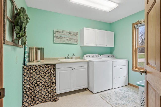 clothes washing area with washer and dryer, a wealth of natural light, sink, and cabinets