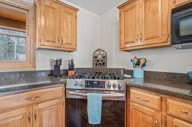 kitchen with stainless steel range with gas cooktop and dark stone countertops