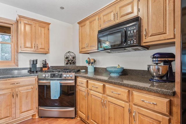 kitchen with dark stone countertops, light hardwood / wood-style floors, and stainless steel gas range oven