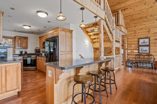 kitchen featuring pendant lighting, black appliances, a center island, dark hardwood / wood-style floors, and rustic walls