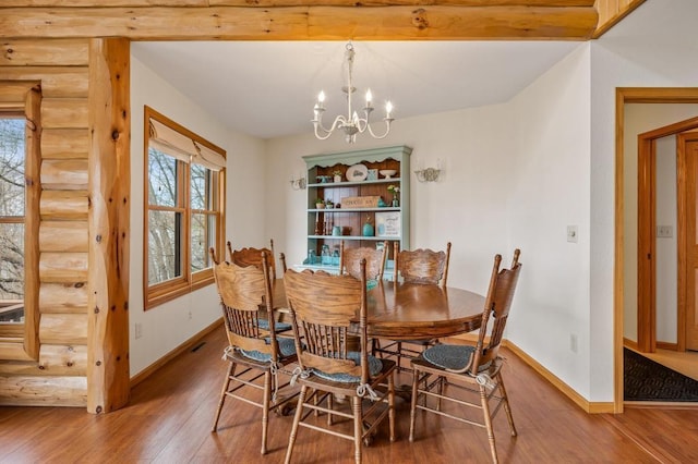 dining room with hardwood / wood-style flooring, rustic walls, and a notable chandelier