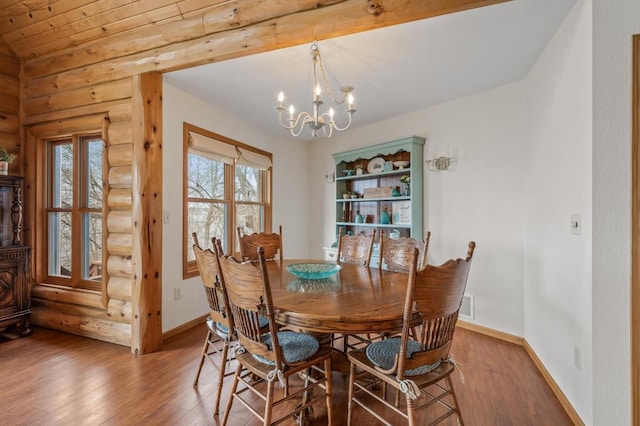 dining space with hardwood / wood-style flooring, rustic walls, and an inviting chandelier