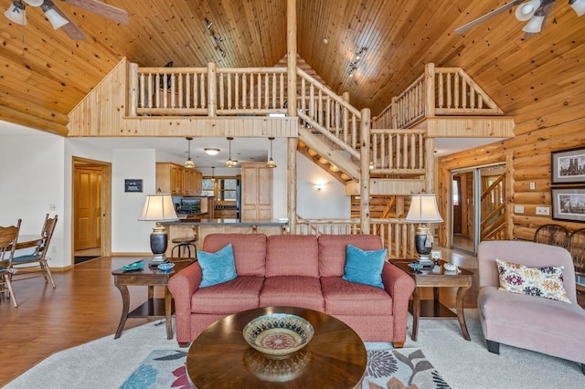 living room featuring rustic walls, light hardwood / wood-style floors, wooden ceiling, and high vaulted ceiling