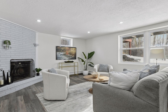 living room featuring a textured ceiling, a brick fireplace, a wealth of natural light, and dark hardwood / wood-style floors