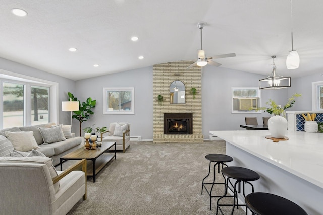 carpeted living room featuring vaulted ceiling, ceiling fan with notable chandelier, baseboard heating, and a fireplace