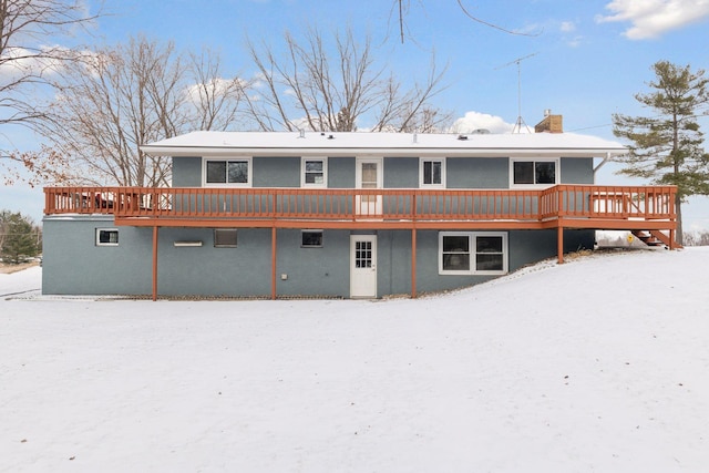 snow covered back of property with a deck