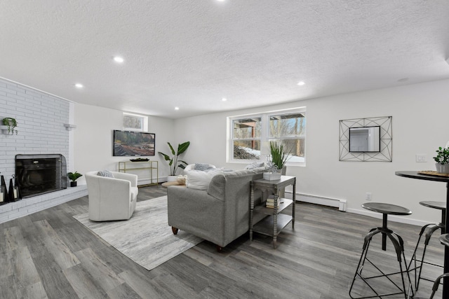 living room with baseboard heating, a fireplace, a textured ceiling, and wood-type flooring