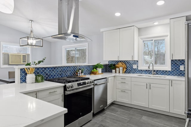 kitchen with sink, hanging light fixtures, appliances with stainless steel finishes, white cabinets, and island range hood