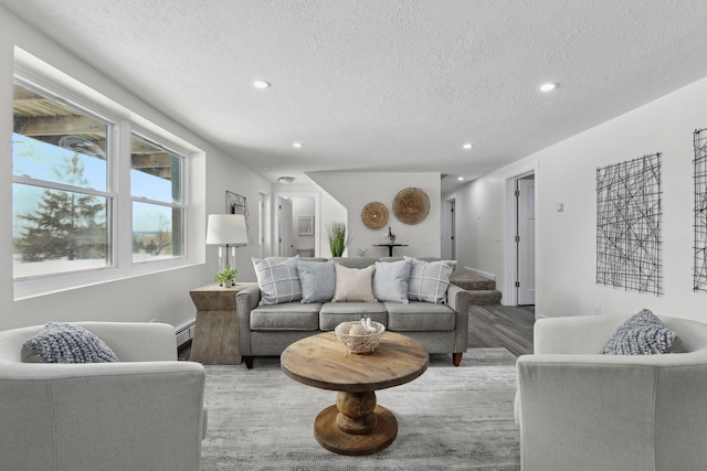 living room featuring light wood-type flooring, a textured ceiling, and a baseboard heating unit