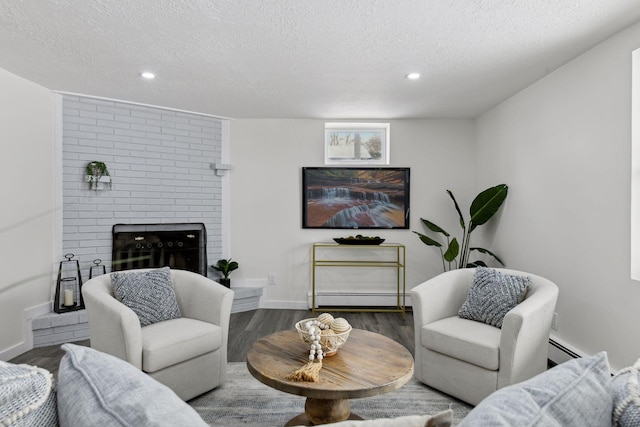 living room featuring a textured ceiling, a brick fireplace, a baseboard heating unit, and dark wood-type flooring