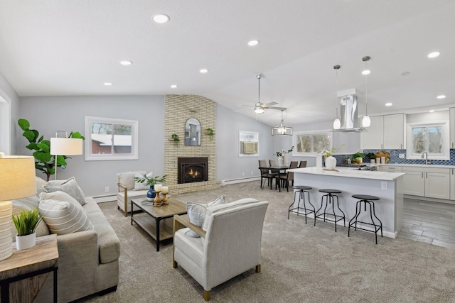 living room with ceiling fan, baseboard heating, a brick fireplace, and sink