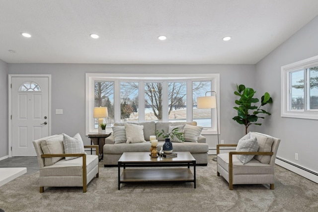 living room with a baseboard heating unit, plenty of natural light, and vaulted ceiling