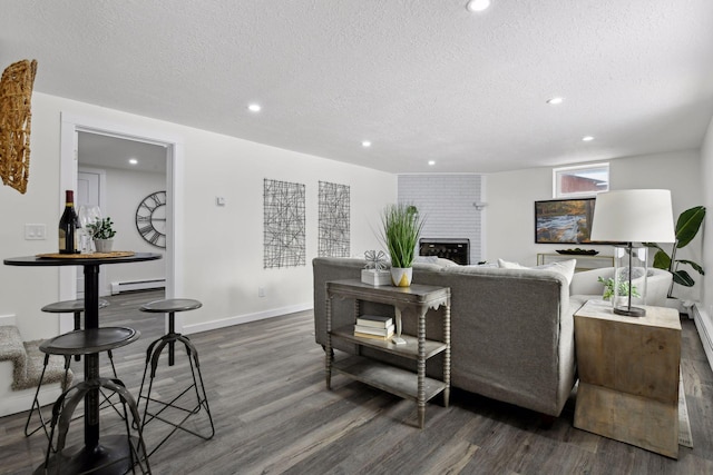 living room featuring a brick fireplace, a baseboard radiator, a textured ceiling, and dark wood-type flooring