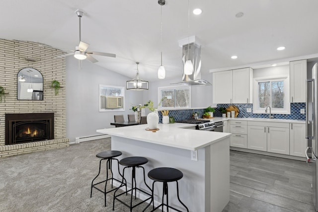 kitchen with island exhaust hood, stainless steel gas range, white cabinets, and a breakfast bar area