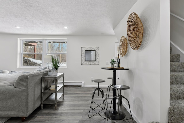 living room with dark hardwood / wood-style flooring, a baseboard heating unit, and a textured ceiling