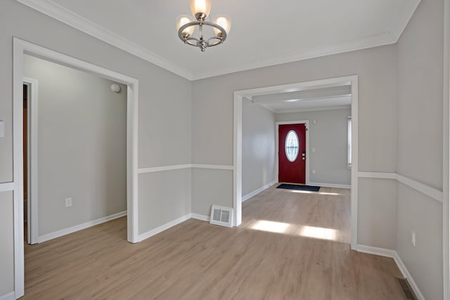 foyer entrance with light wood-type flooring, an inviting chandelier, and crown molding