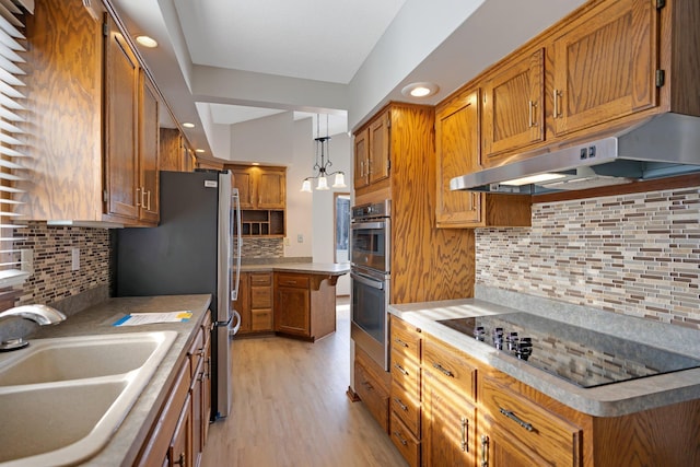 kitchen featuring decorative light fixtures, backsplash, black electric stovetop, sink, and light hardwood / wood-style flooring